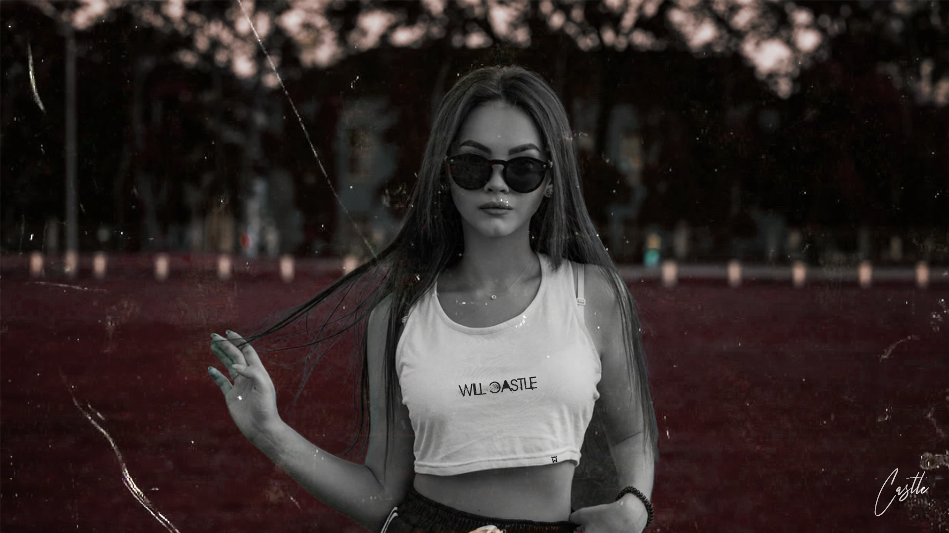 A woman wearing sunglasses and a crop top is standing in front of a red wall.