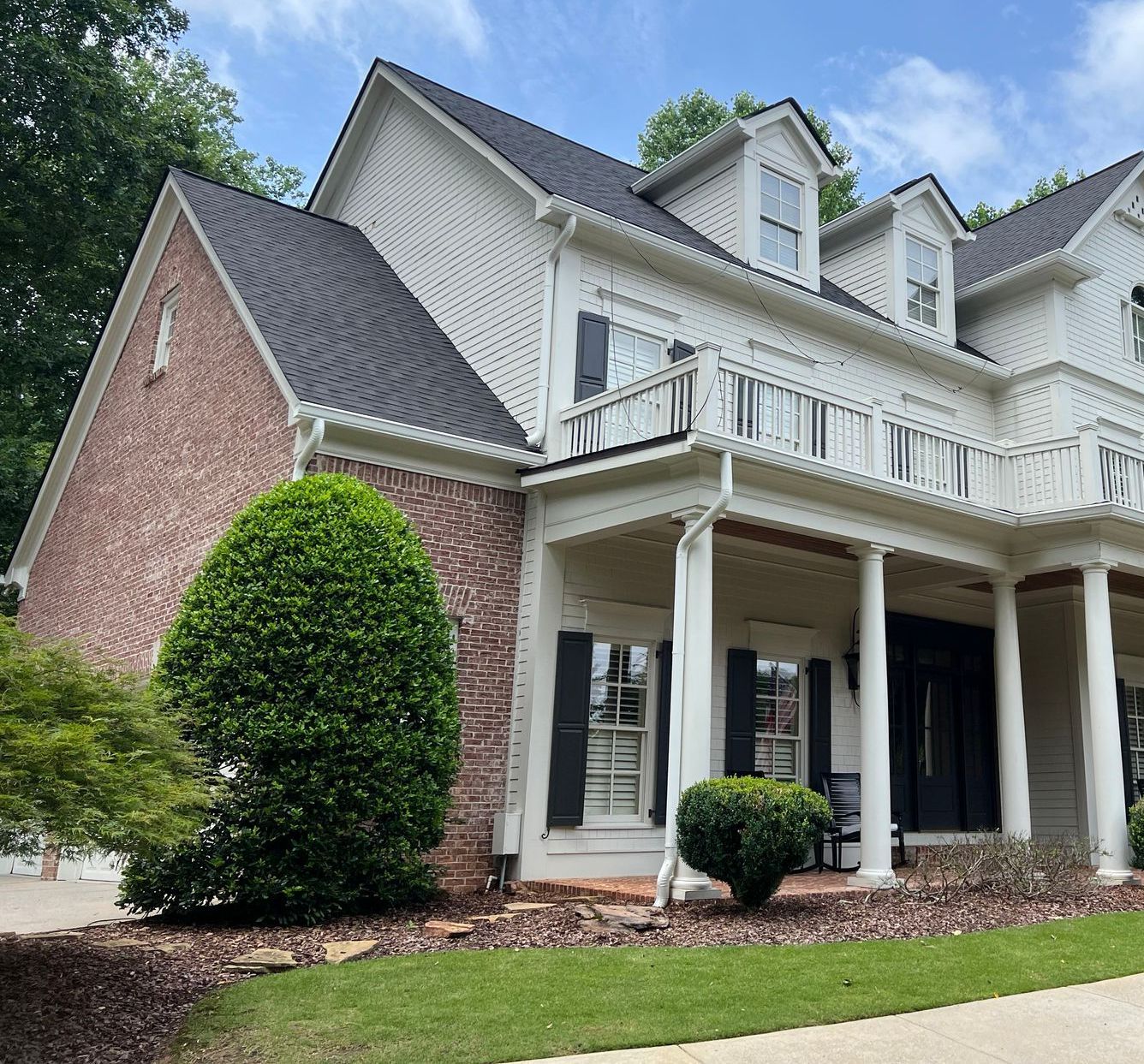 A large white house with a black roof and a large porch