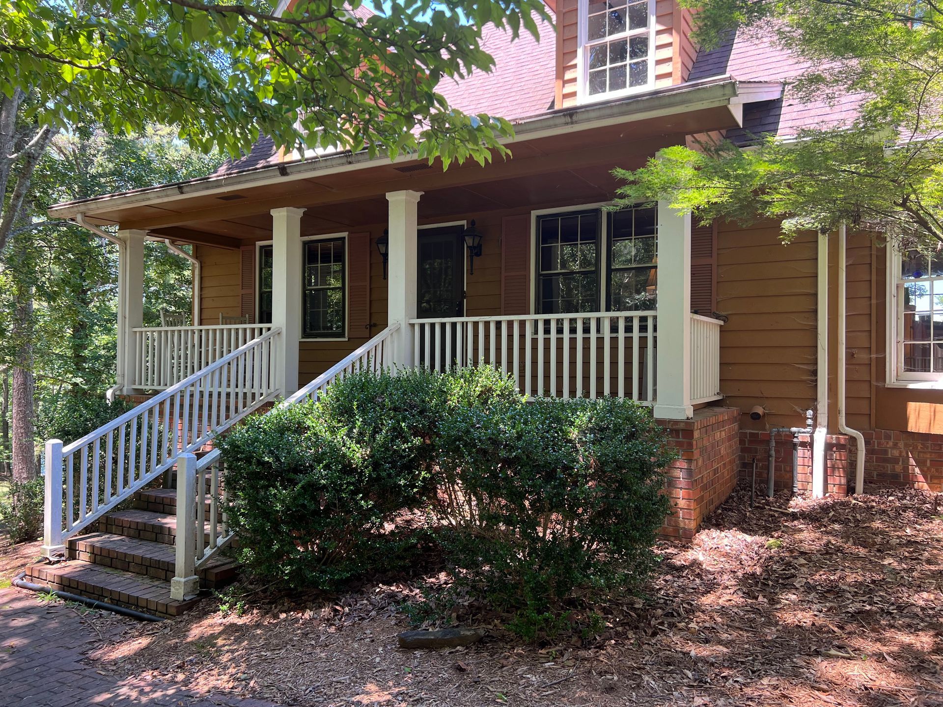 A brown house with a white porch and stairs.