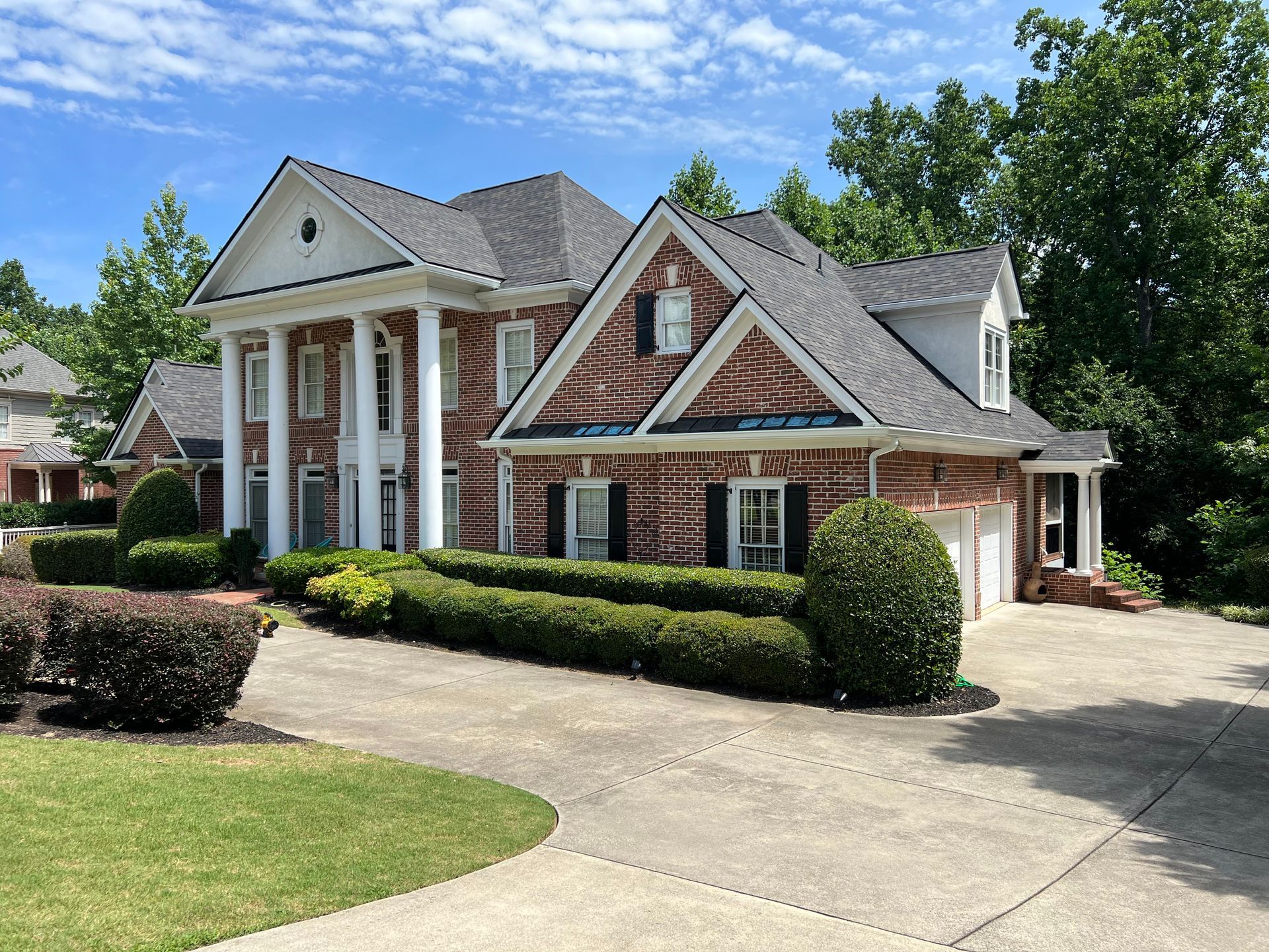 A large brick house with a gray roof and white trim