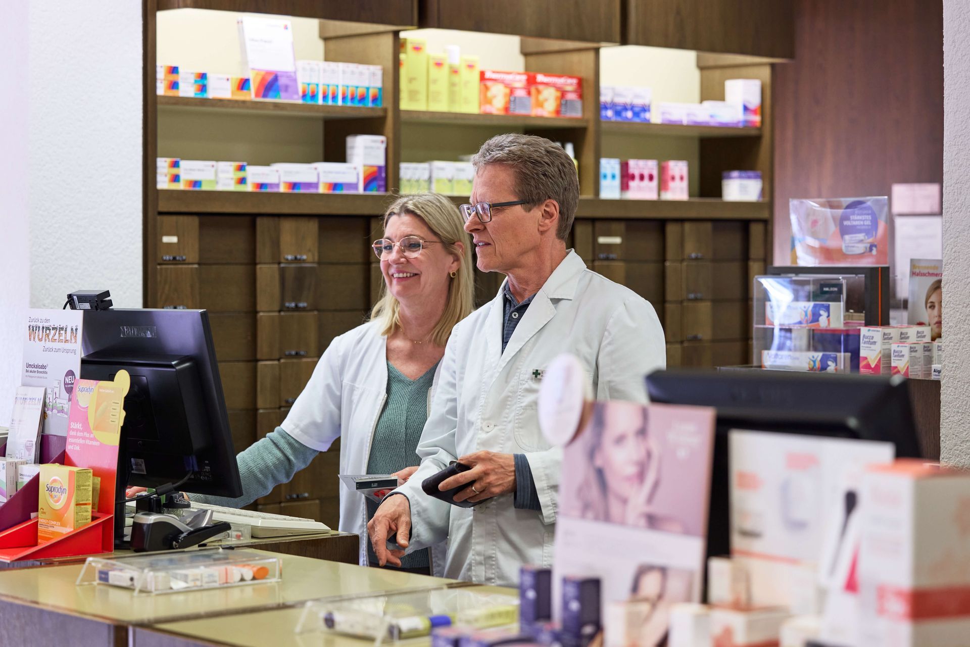 Ein Mann und eine Frau arbeiten in einer Apotheke.
