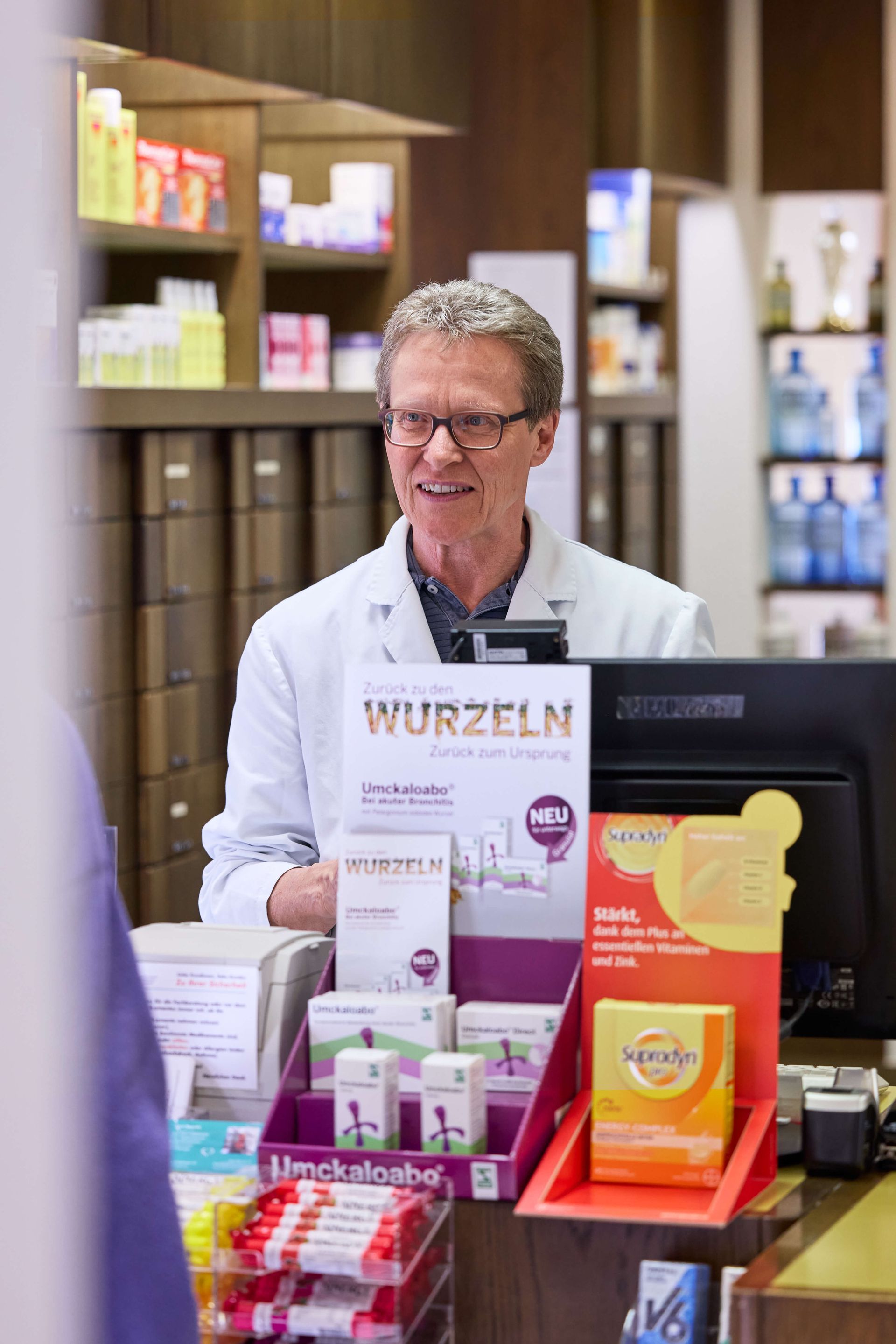 Ein Mann steht an einem Tresen in einer Apotheke.