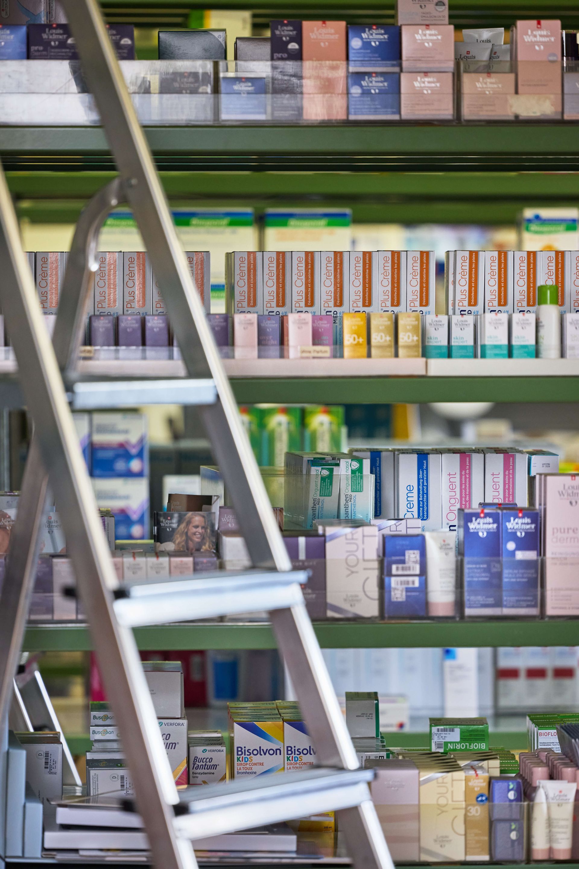 In einer Apotheke steht eine Leiter auf einem Regal.