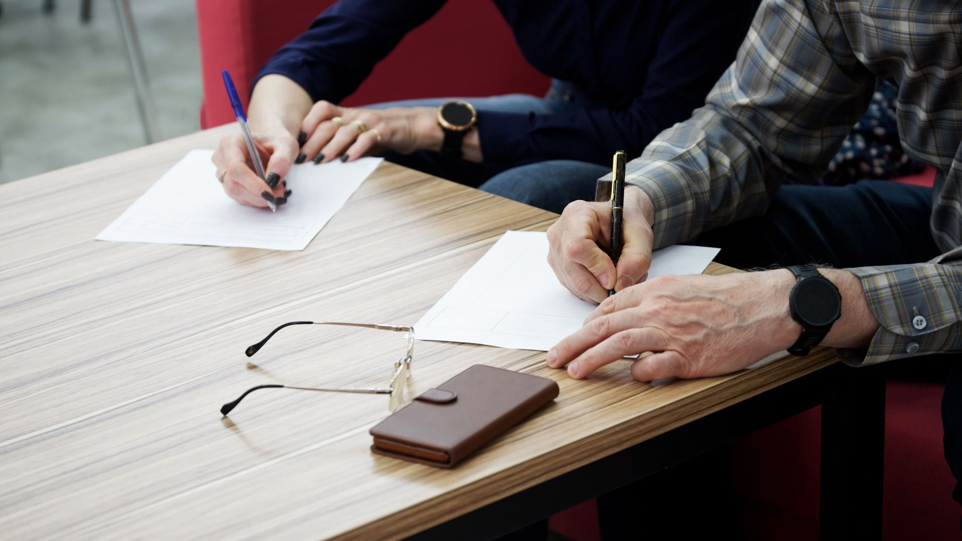 A man and a woman are sitting at a table writing on papers.