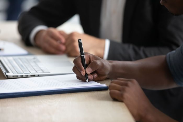 A person is writing on a piece of paper with a pen.