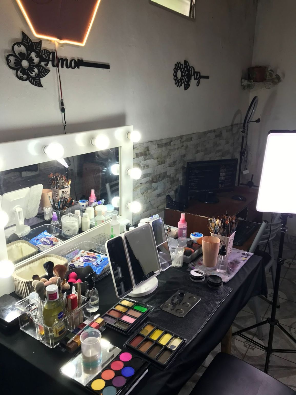 Tocador de maquillaje con espejo iluminado, productos de maquillaje y accesorios.