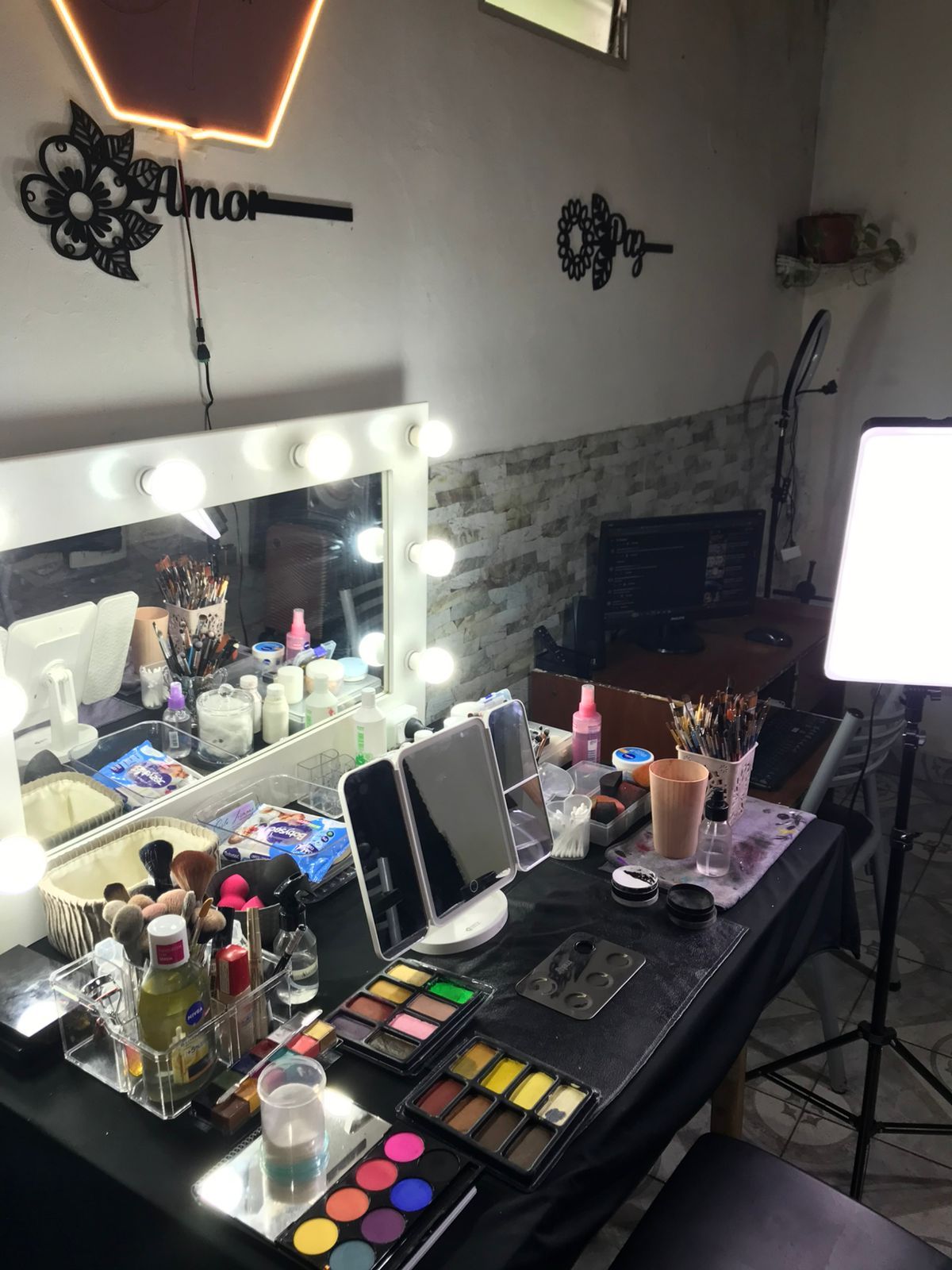 Tocador de maquillaje con espejo iluminado, productos de maquillaje y accesorios.