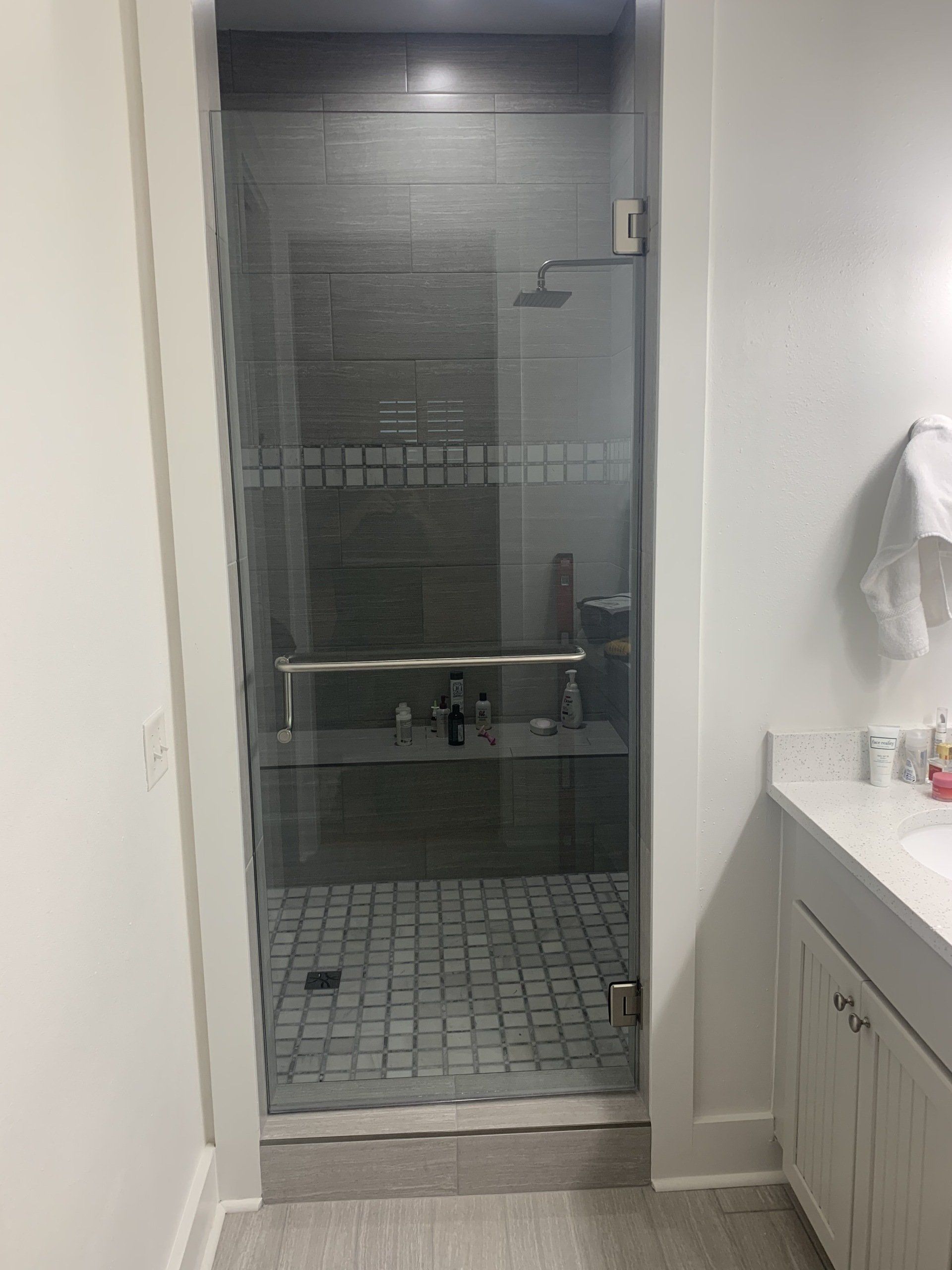 tile shower enclosure with glass swinging door and large chrome handle
