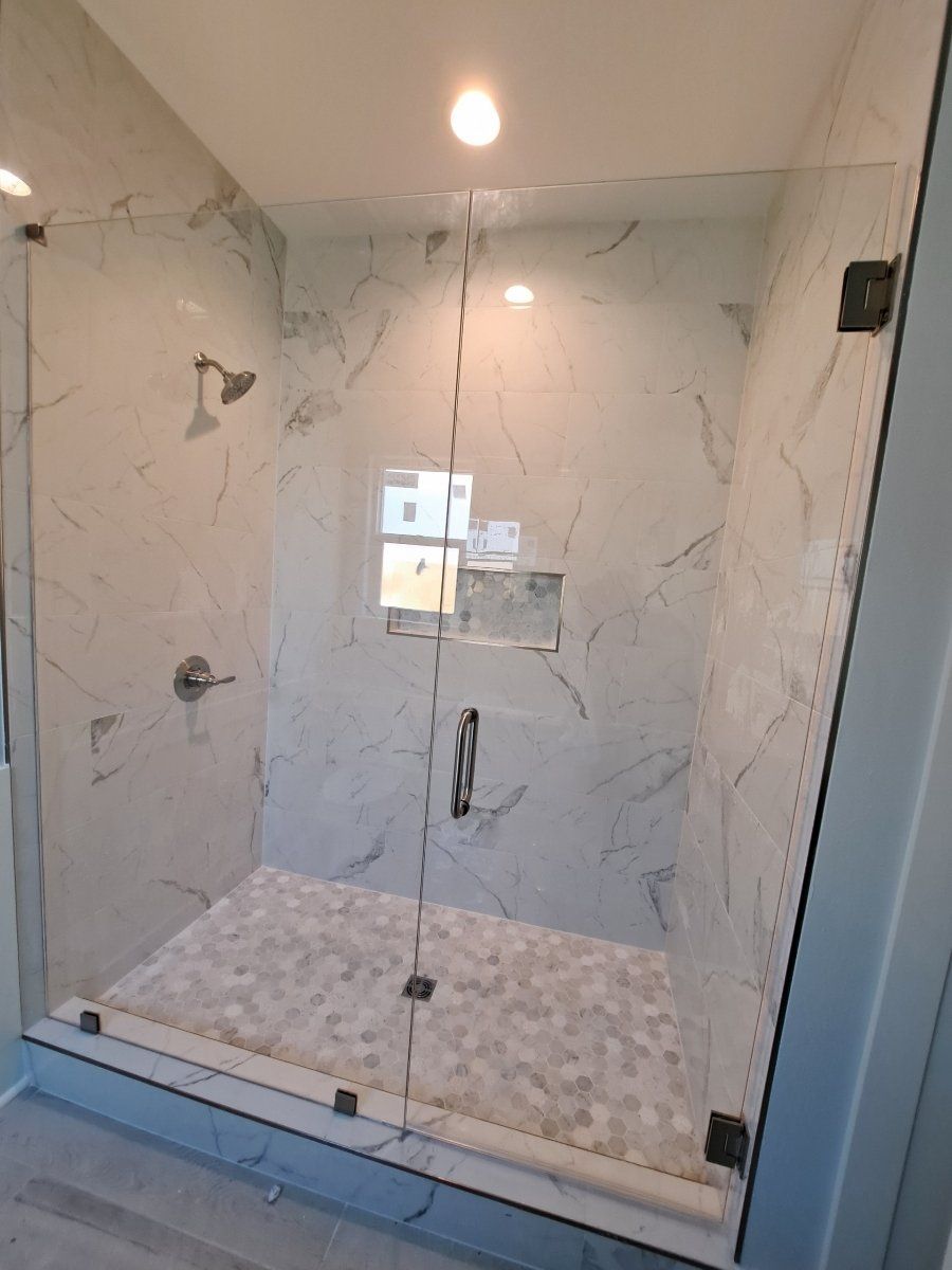 glass shower doors with chrome hardware and white marble surround