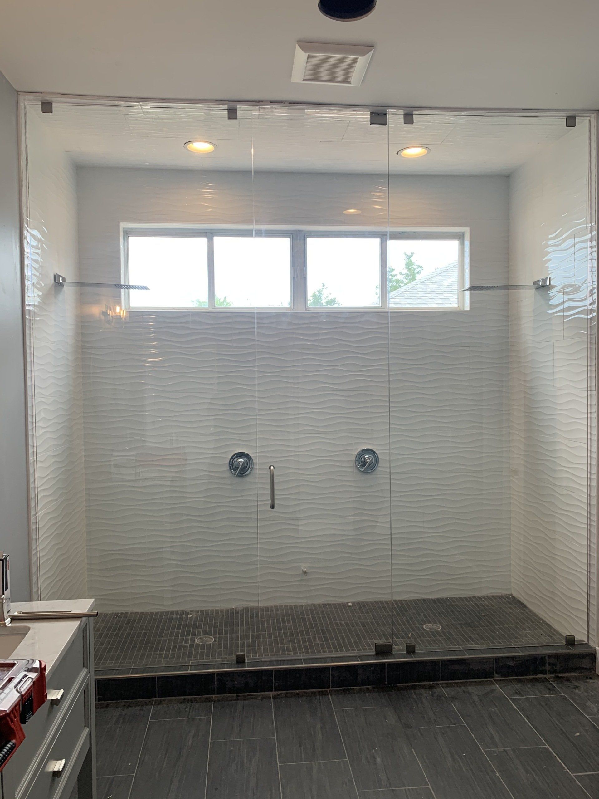 glass shower door with chrome hardware and white tile walls