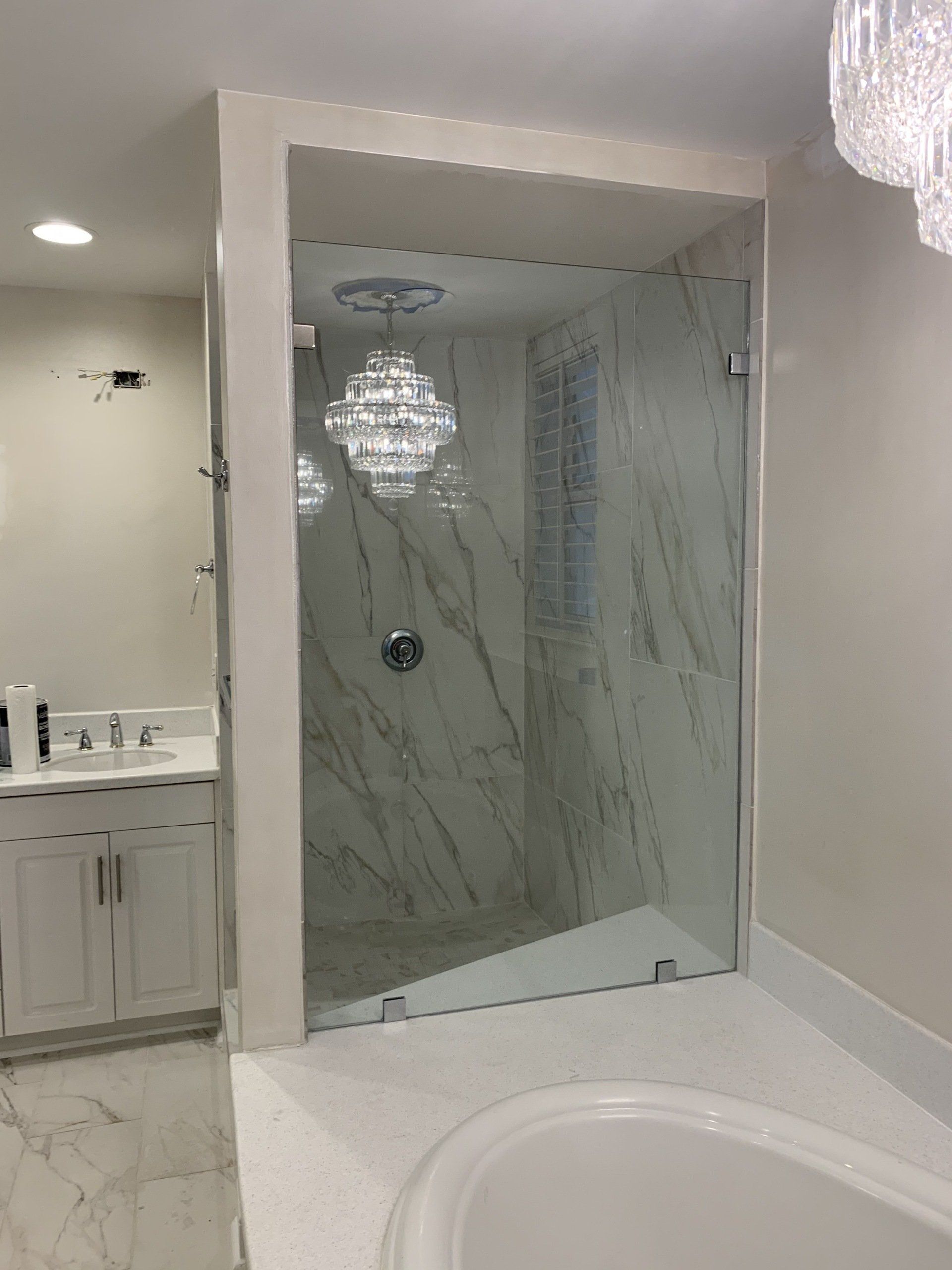 white bathroom shower with marble walls and glass door
