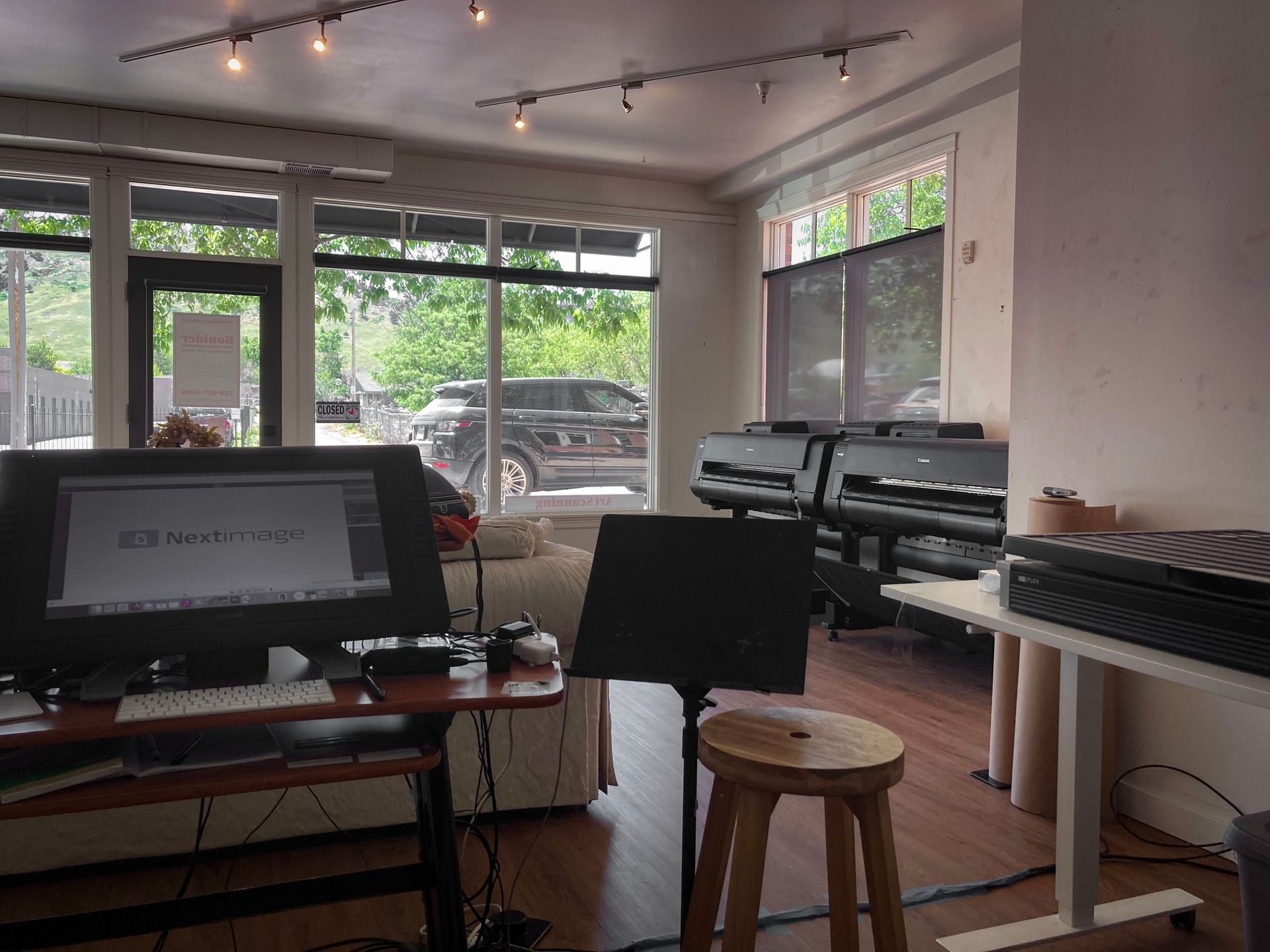 A room with a computer on a desk and a stool