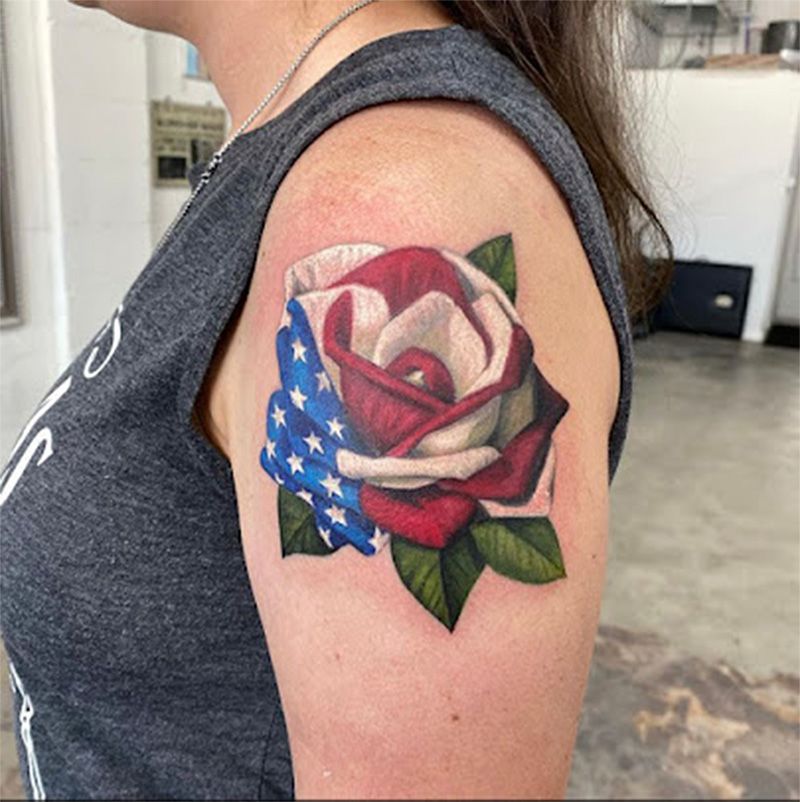 A woman has a tattoo of an american flag rose on her shoulder.