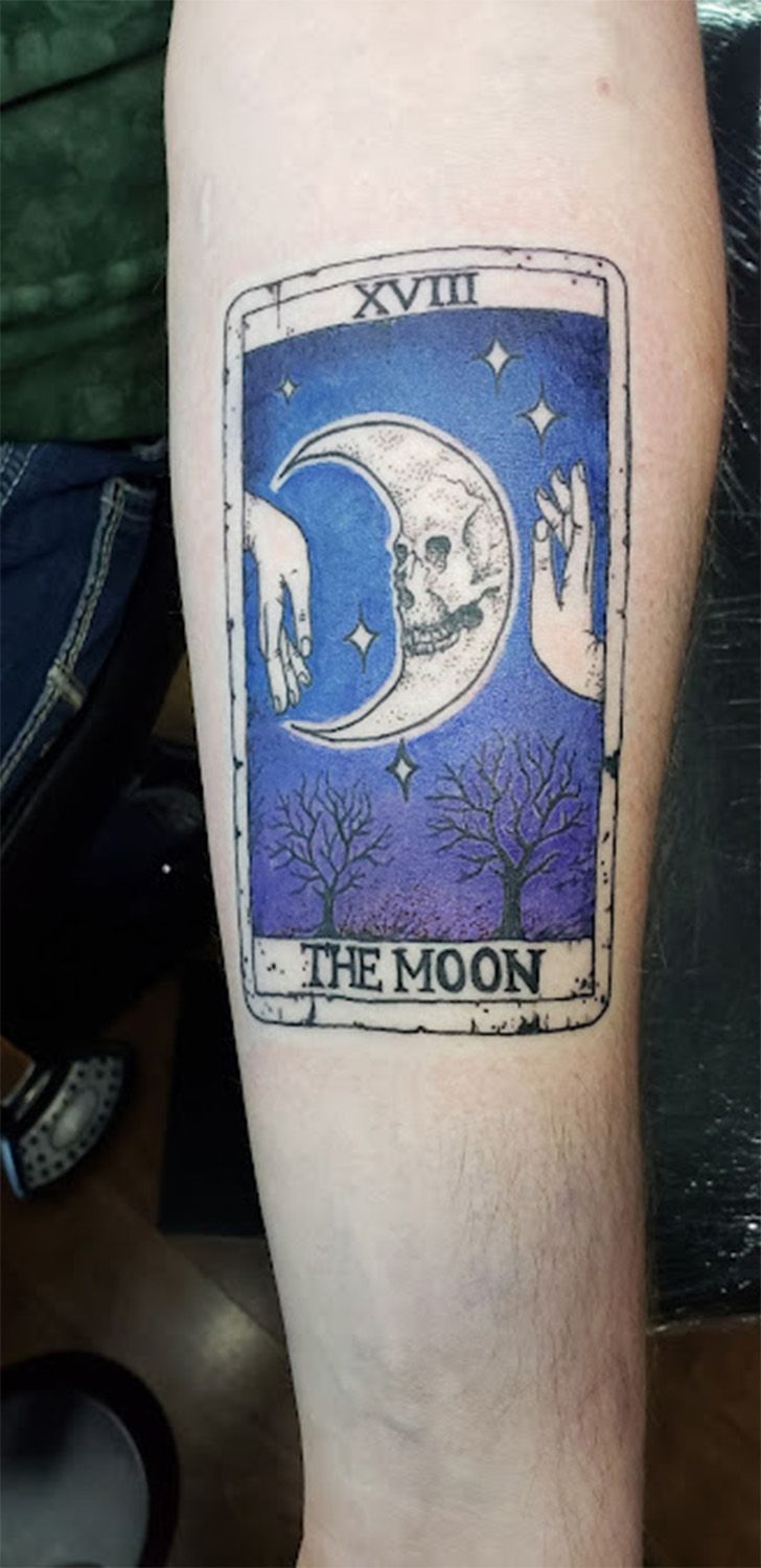 A person has a tattoo of a tarot card on their arm.