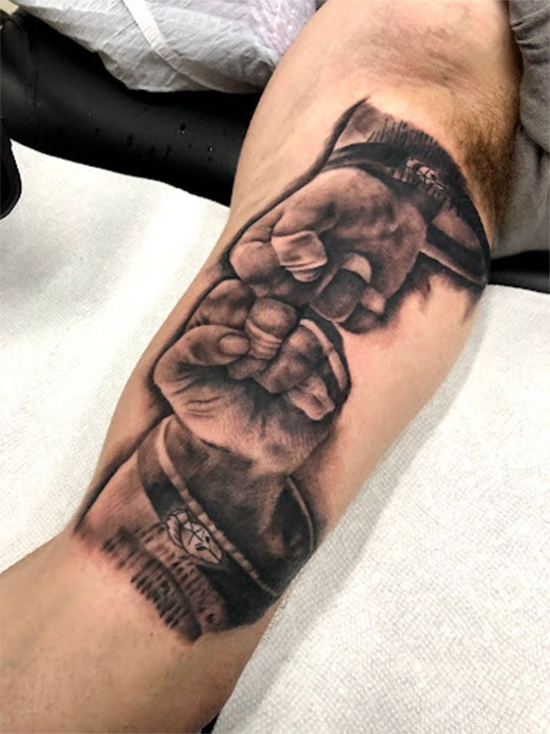 A man has a tattoo of a fist on his forearm.