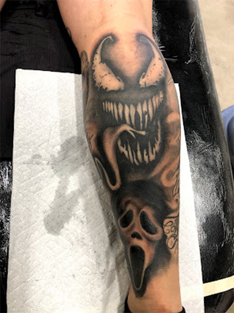 A person has a tattoo of a screaming ghost on their arm.