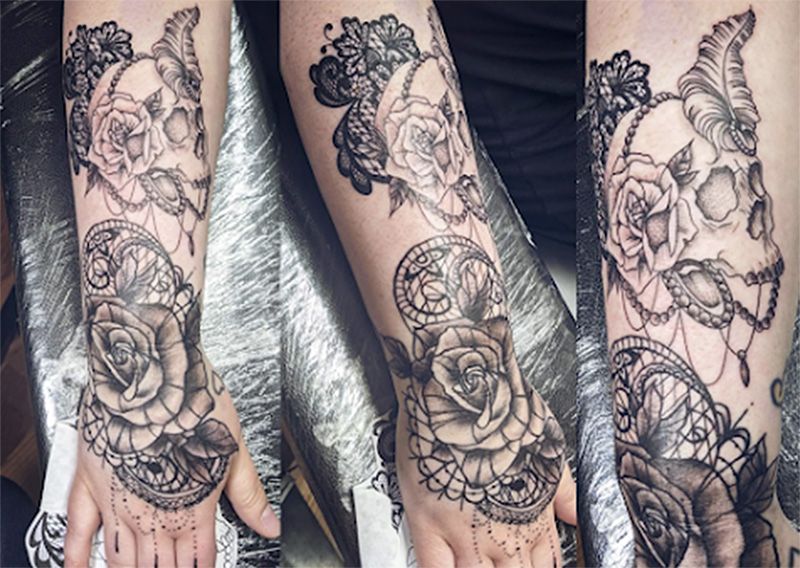 A woman has a tattoo of a skull and roses on her arm