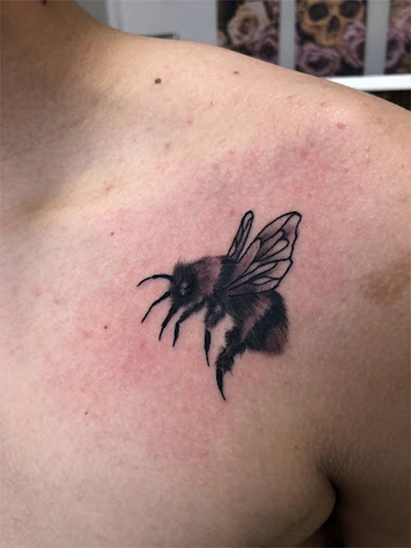 A person has a tattoo of a bee on their shoulder.