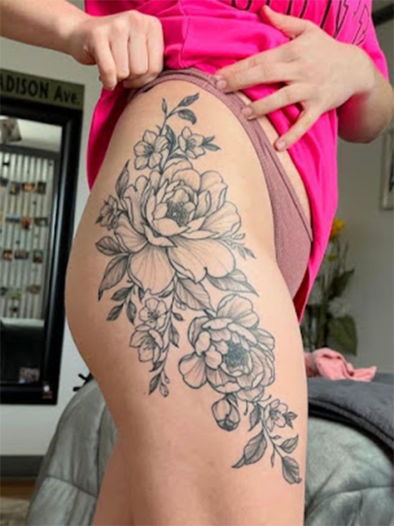 A woman has a tattoo of flowers on her thigh