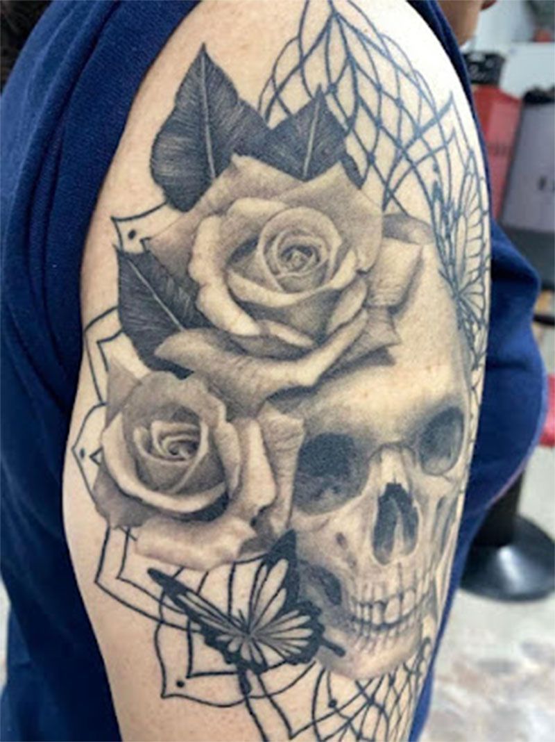A woman has a tattoo of a skull and roses on her arm