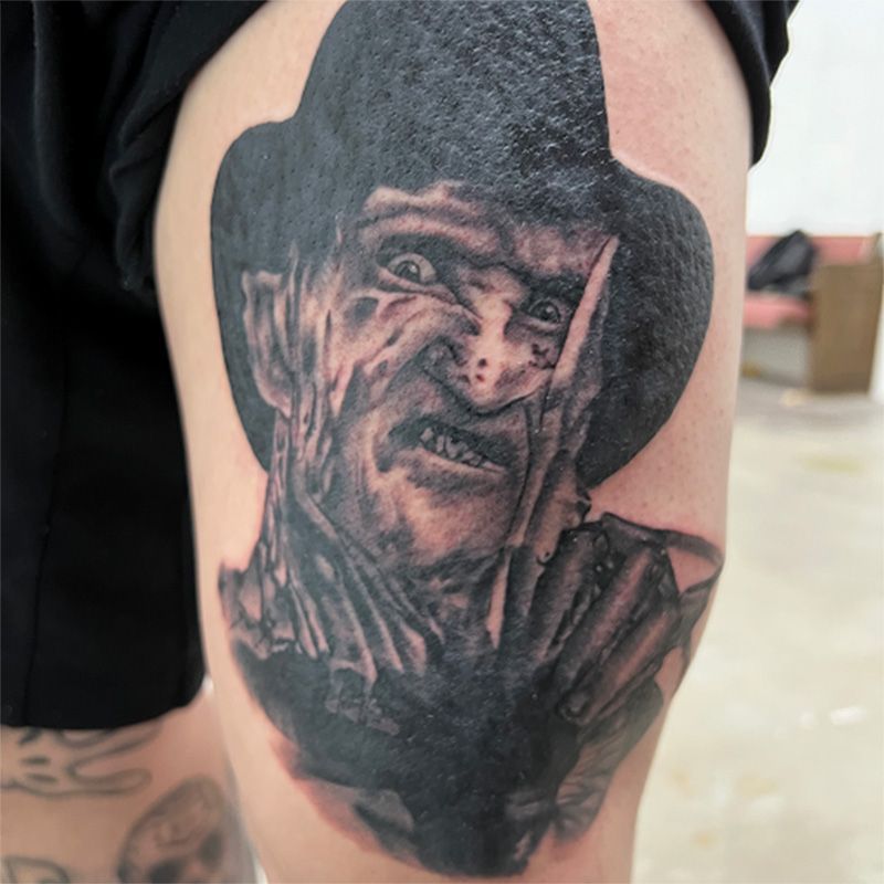 A person has a tattoo of freddy krueger on their leg