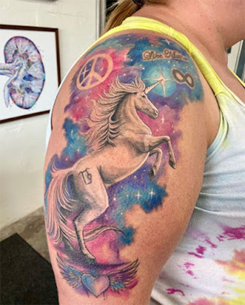 A woman has a tattoo of a unicorn on her shoulder.