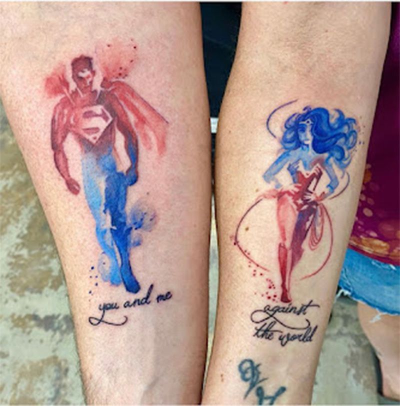 A man and a woman have matching tattoos of superman and wonder woman