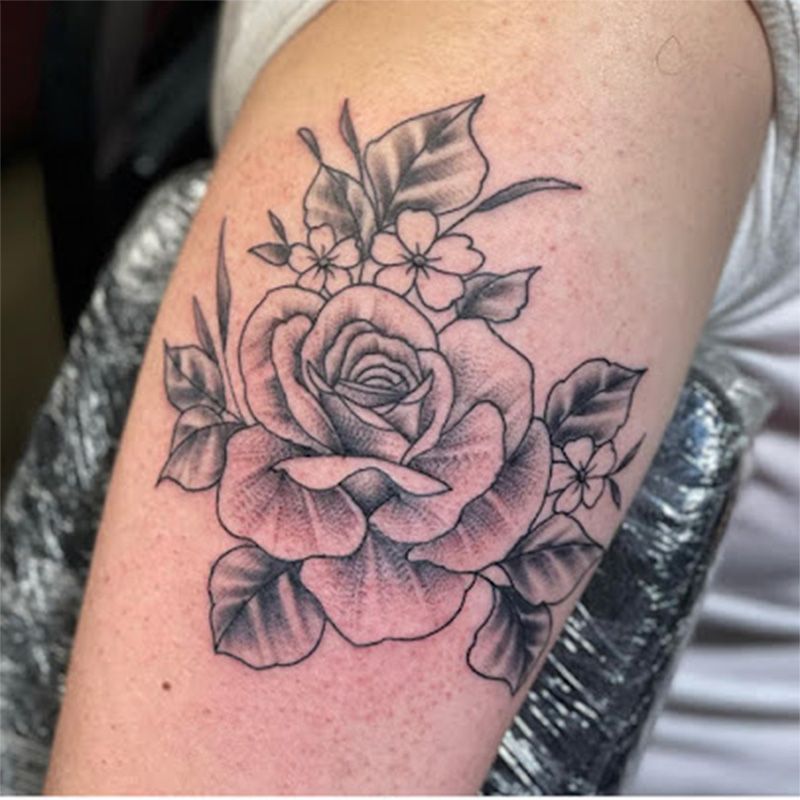 A woman has a tattoo of a rose on her arm
