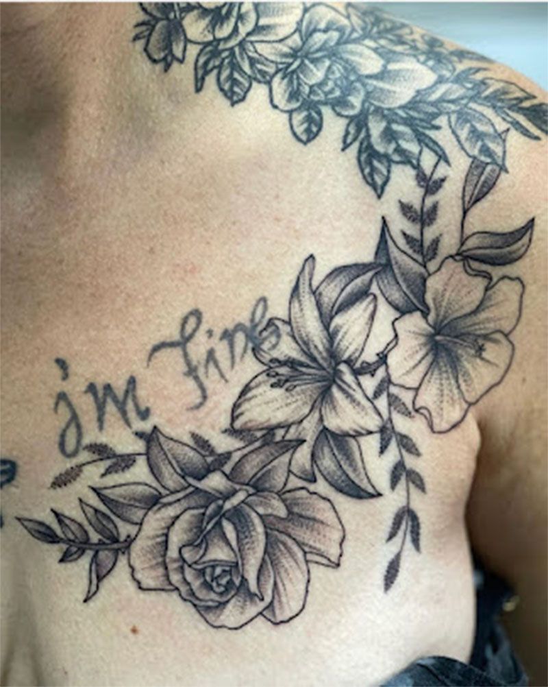 A woman has a tattoo of flowers on her chest and shoulder.