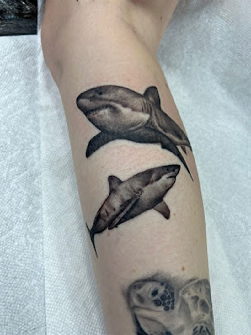 A person has three sharks tattooed on their leg