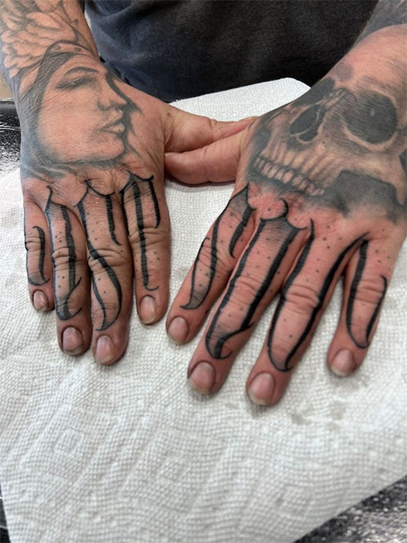 A man 's hands with a skull tattoo on them