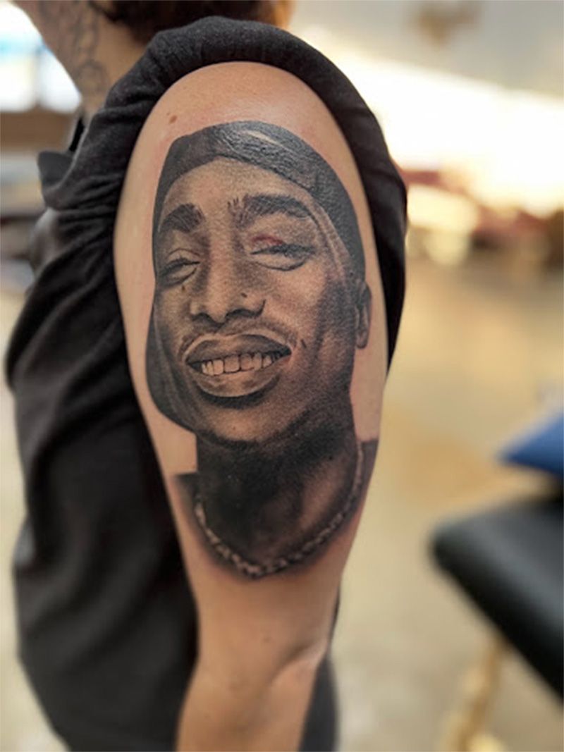 A woman has a tattoo of a smiling man on her arm