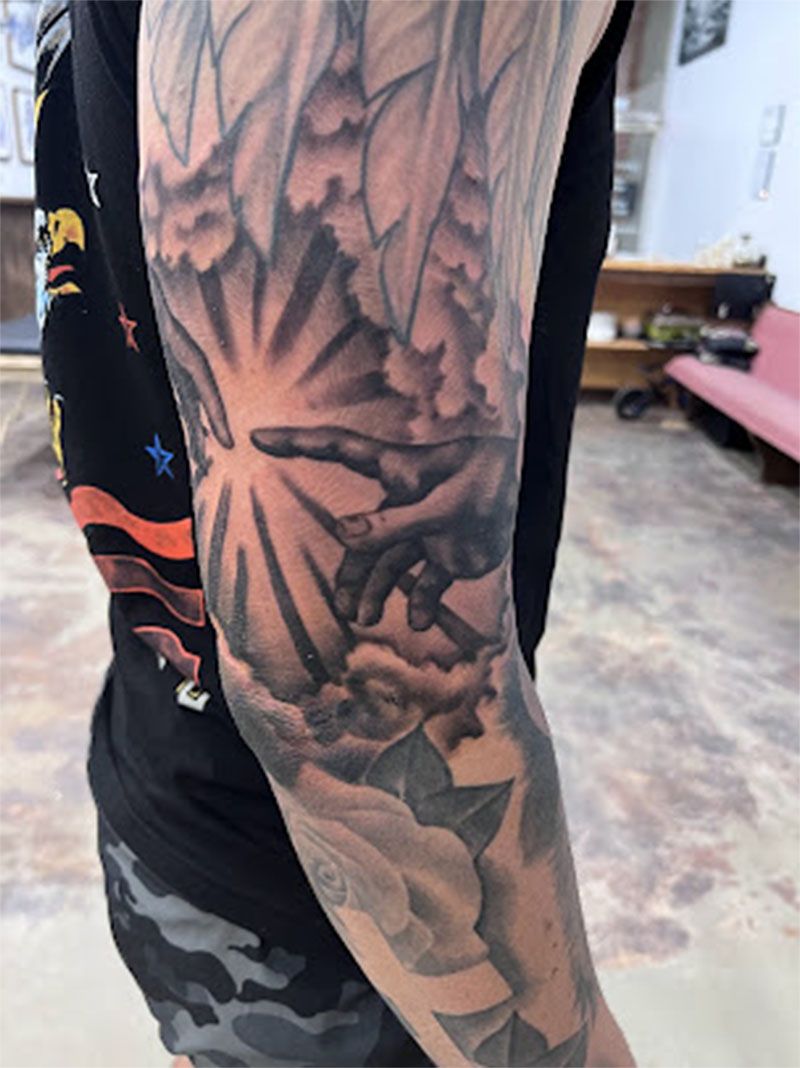 A person with a tattoo on their arm that looks like the creation of adam