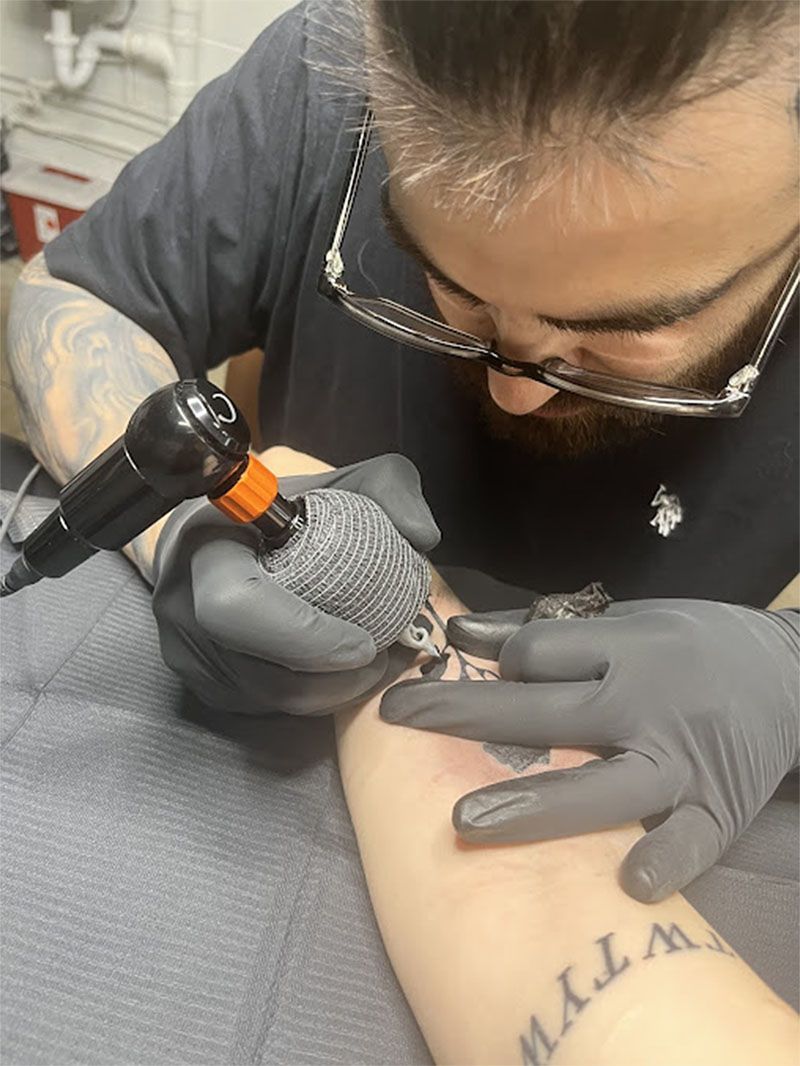 A man is getting a tattoo on a woman 's arm.