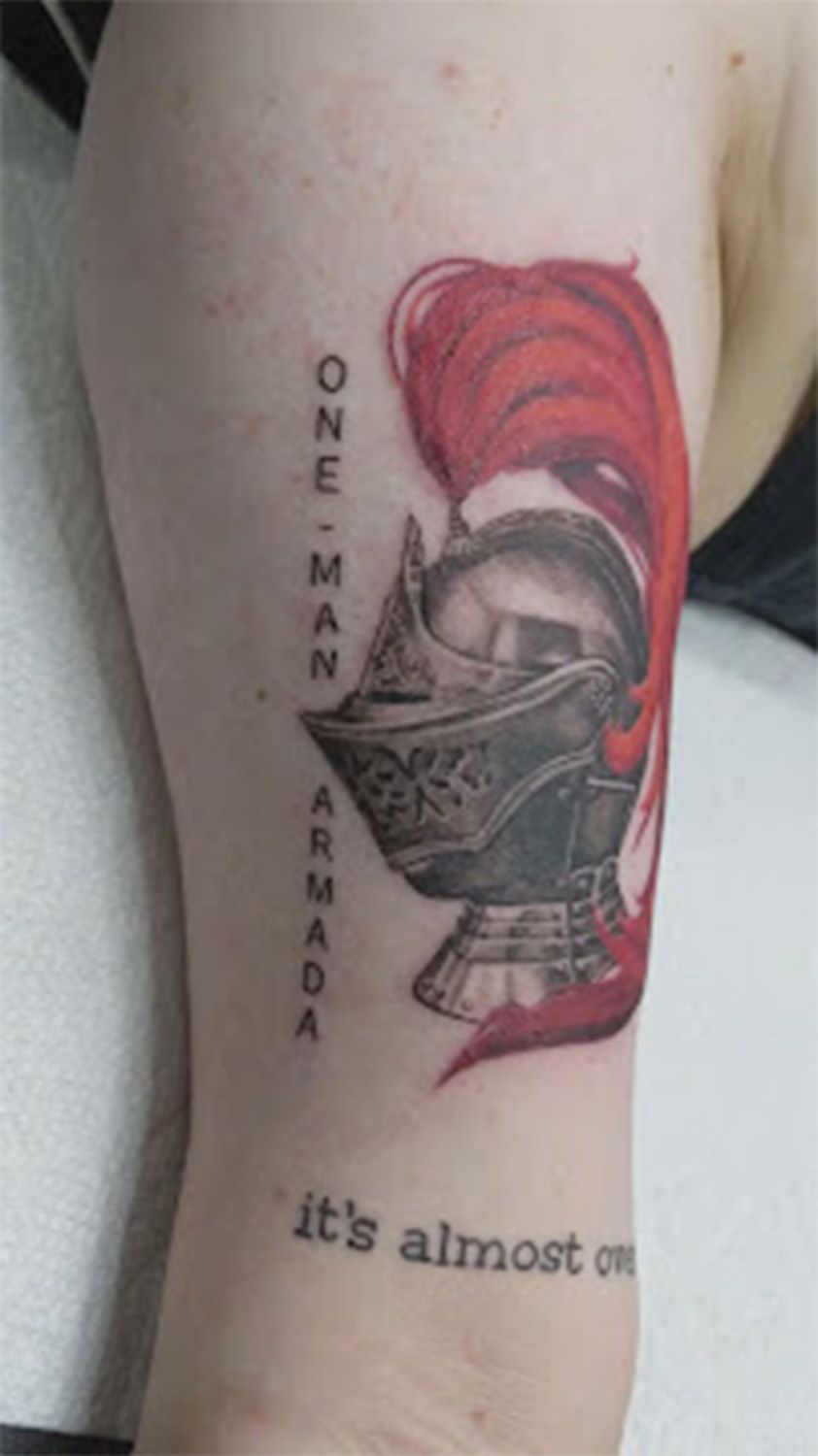 A person has a tattoo of a knight 's helmet on their arm.