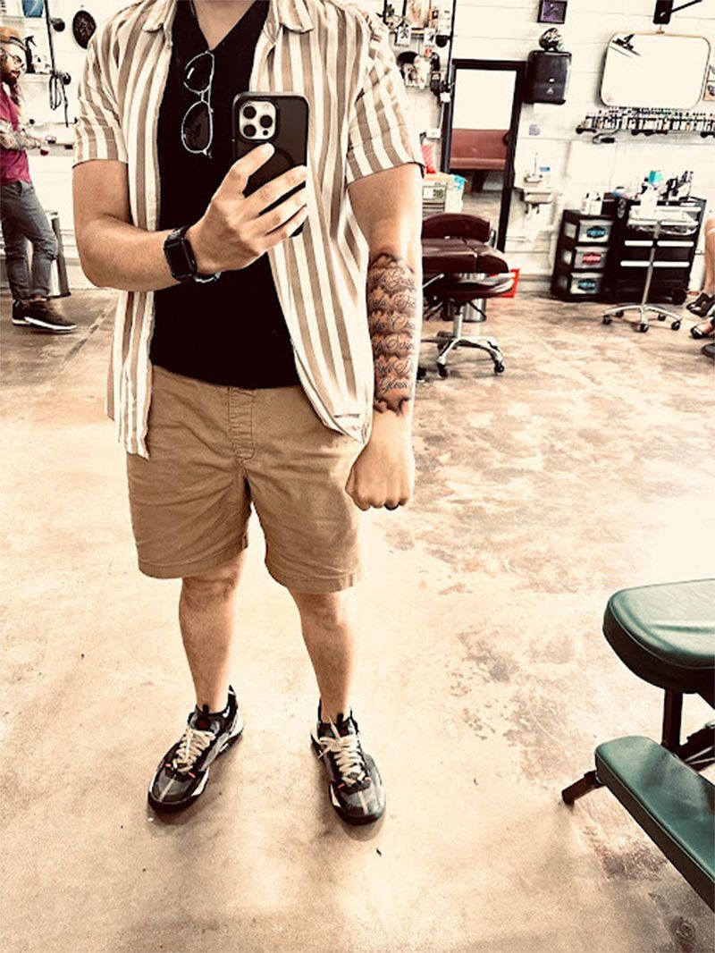 A man is taking a selfie in a tattoo shop.