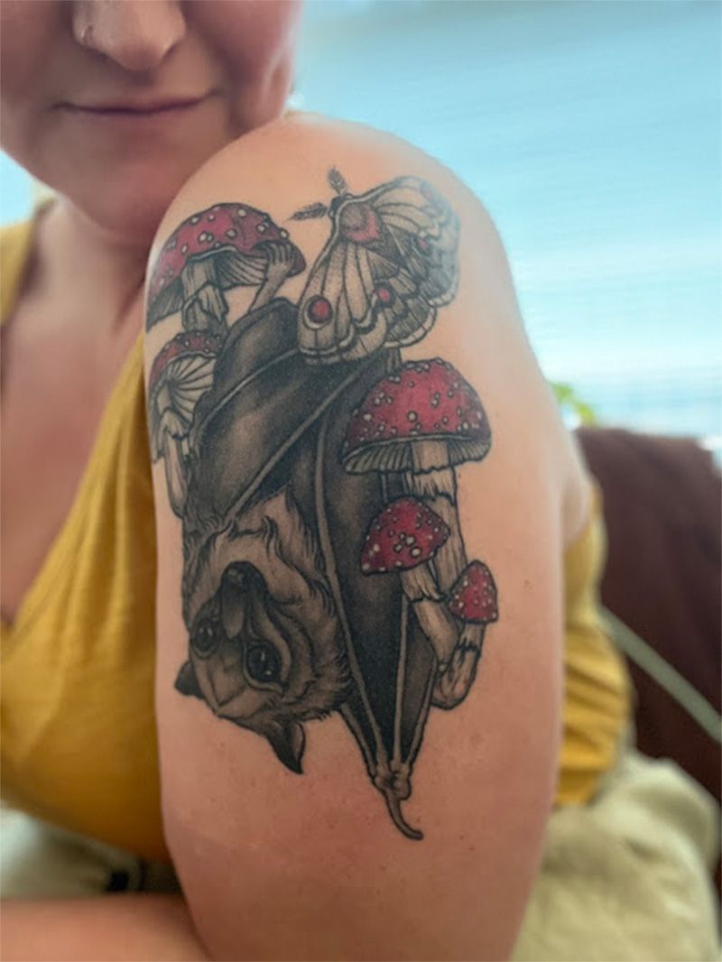 A woman has a bat and mushroom tattoo on her shoulder.