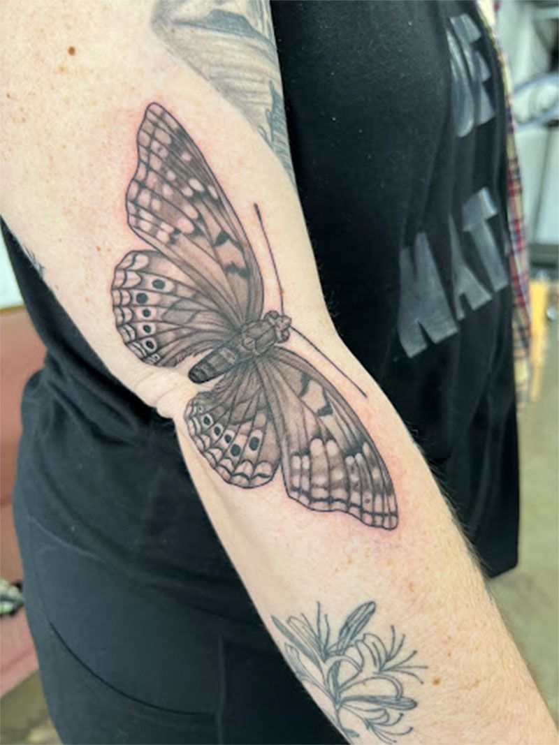 A woman has a tattoo of a butterfly on her arm.