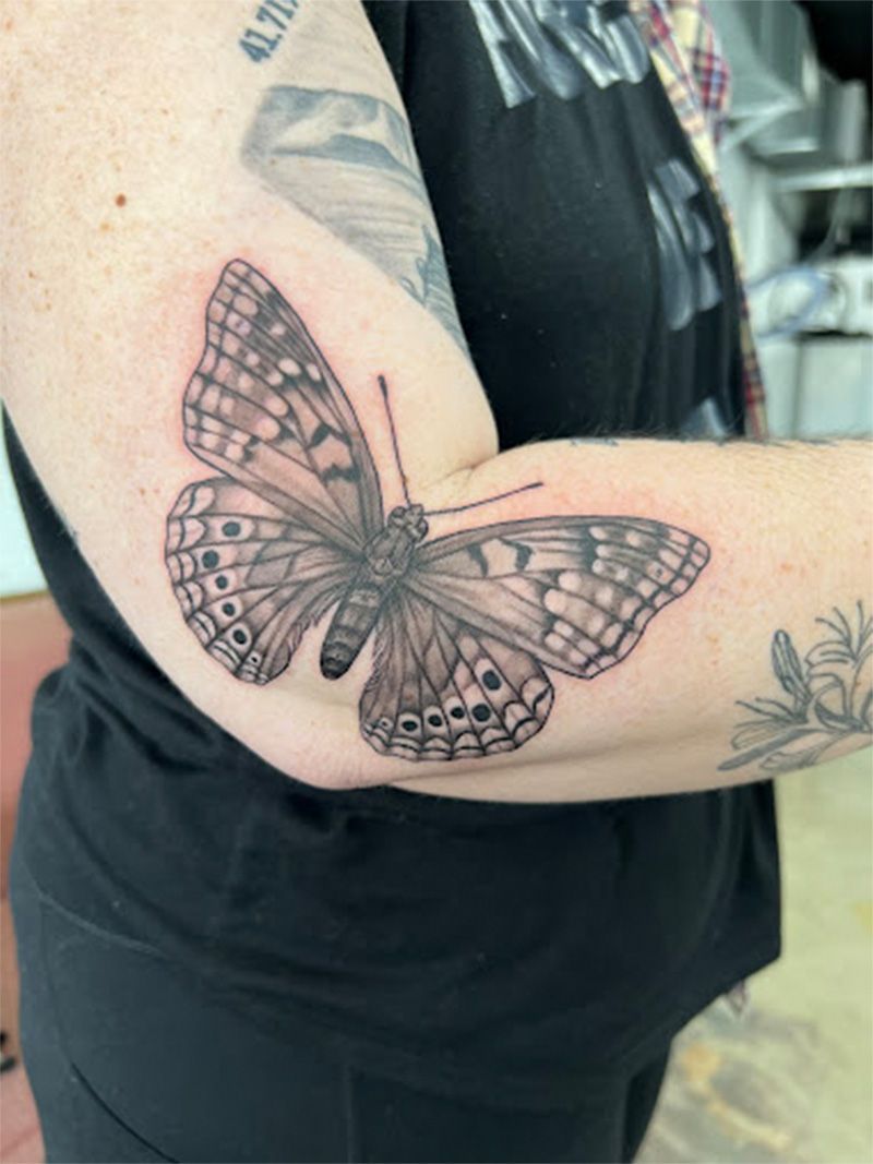 A woman has a tattoo of a butterfly on her elbow.