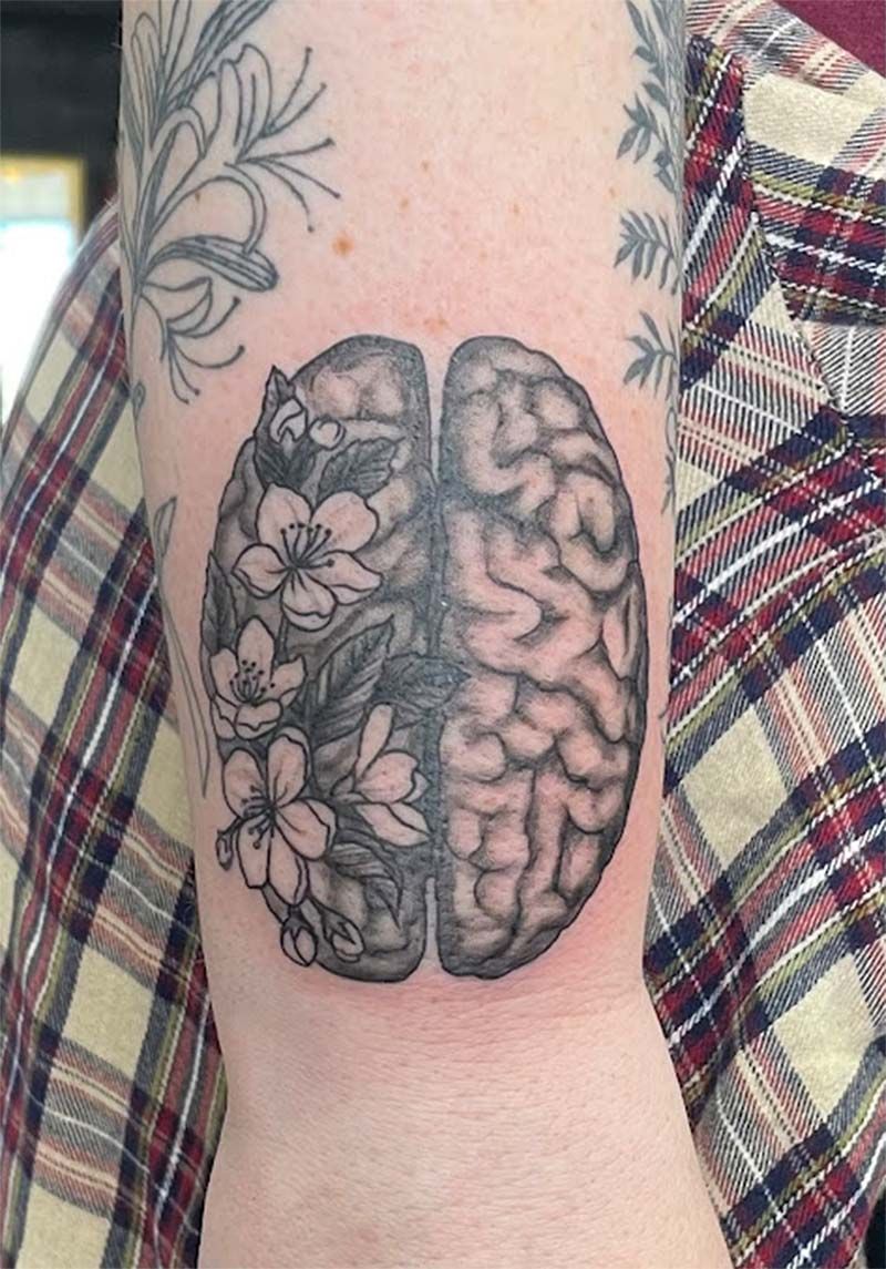 A person has a tattoo of a brain with flowers on it.