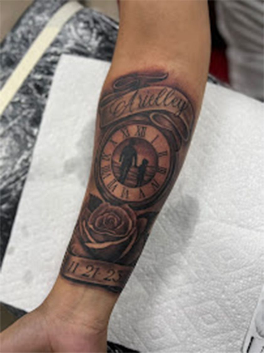 A man has a tattoo of a clock and roses on his forearm