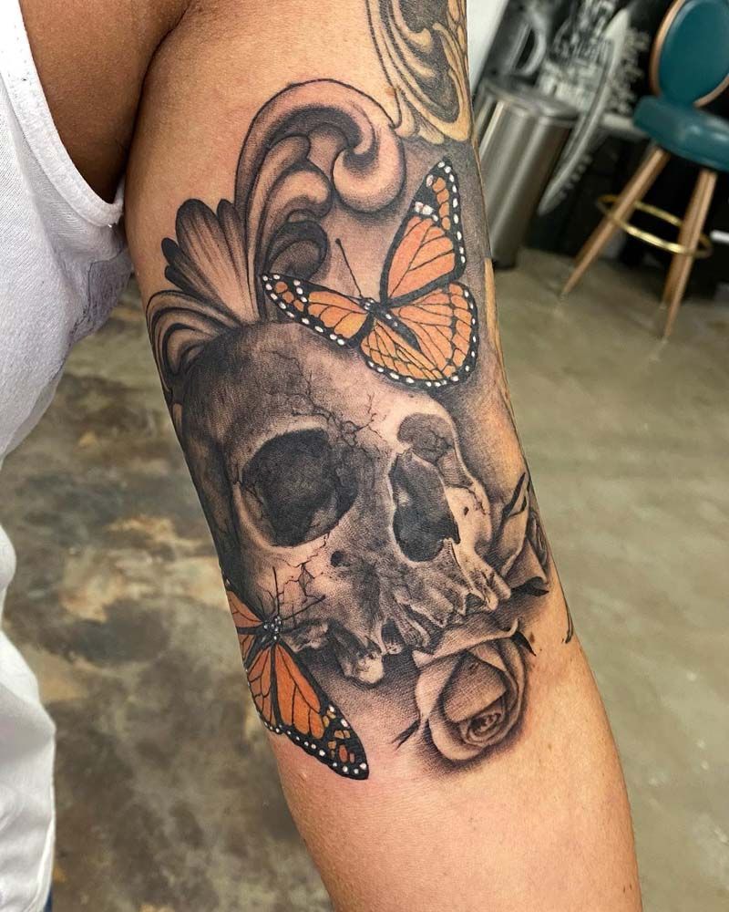 A woman has a tattoo of a skull and butterflies on her arm.