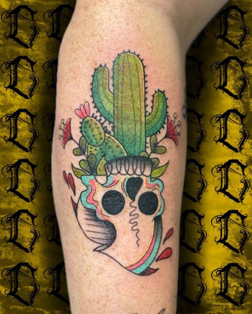 A tattoo of a skull with a cactus inside of it