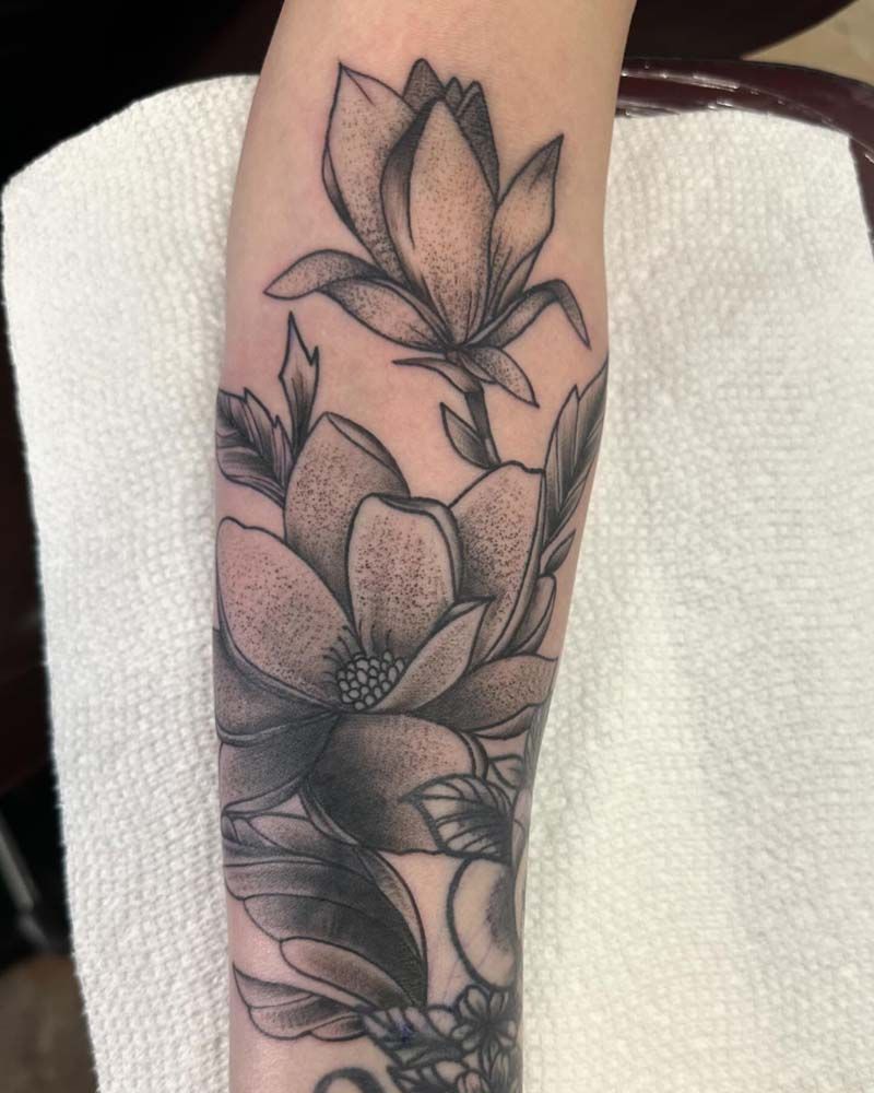 A black and white tattoo of flowers on a person 's forearm