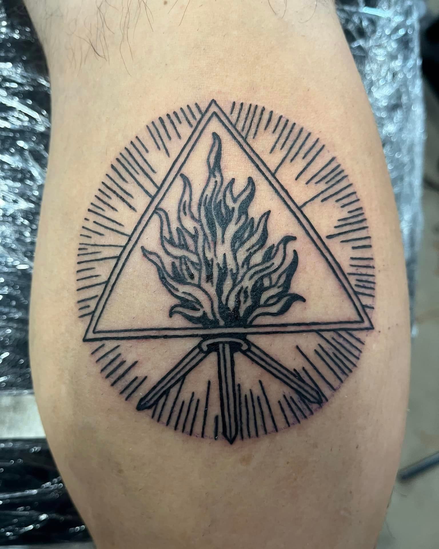 A tattoo of a fire in a triangle on a person 's leg
