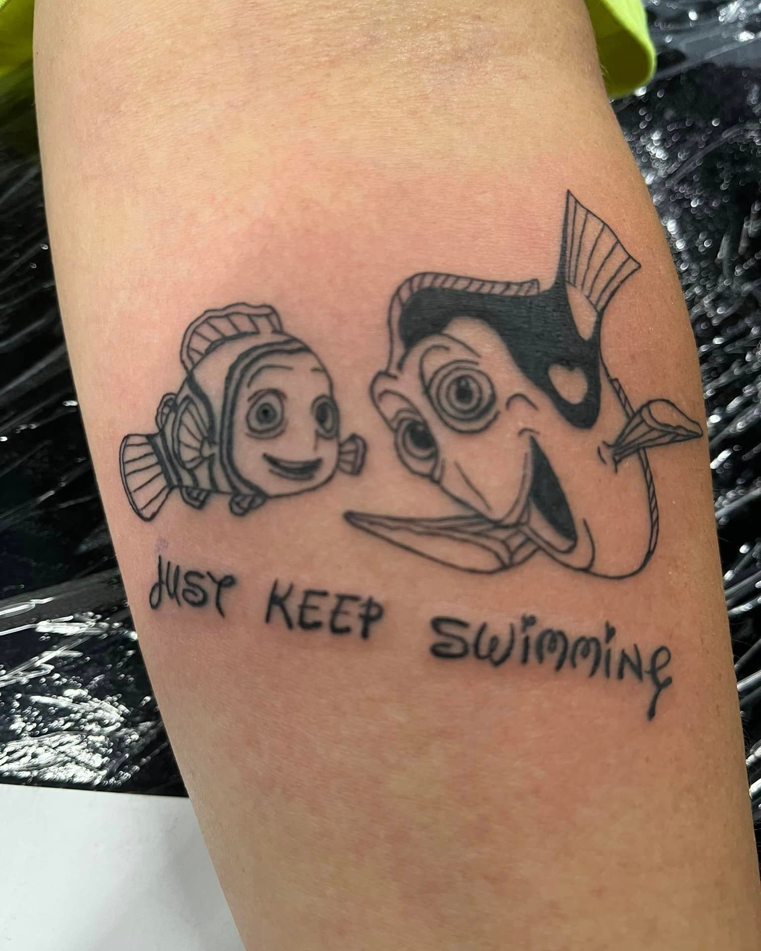 A tattoo on a person 's arm that says just keep swimming