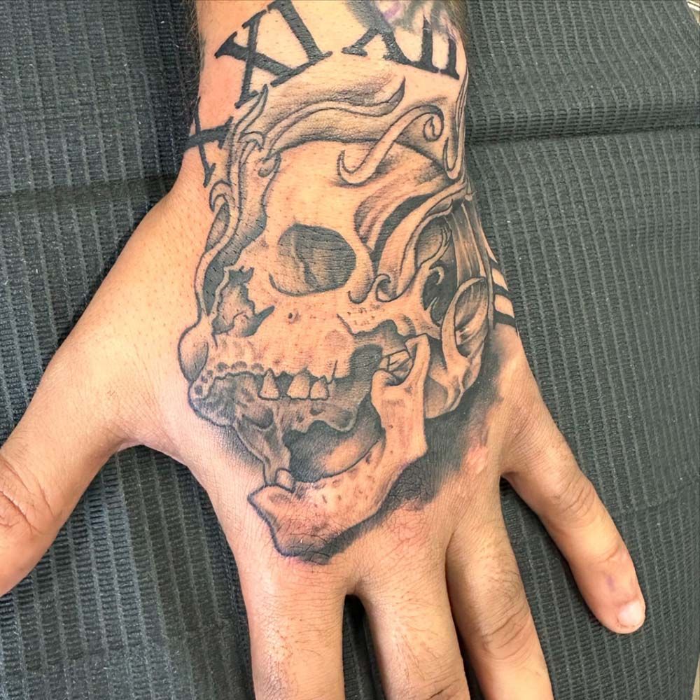 A person has a tattoo of a skull on their hand.