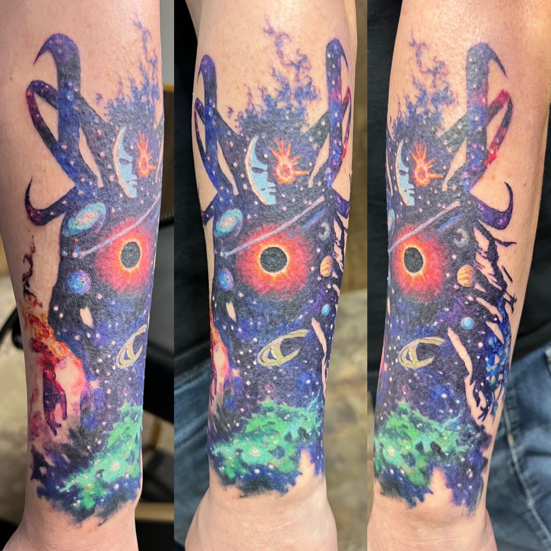 Tattoo of a colorful cosmic scene: swirling nebula, planets, and a black hole on a forearm.