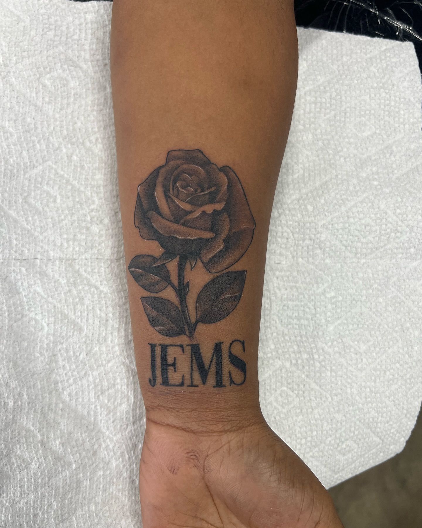 A person has a tattoo of a rose and the name jems