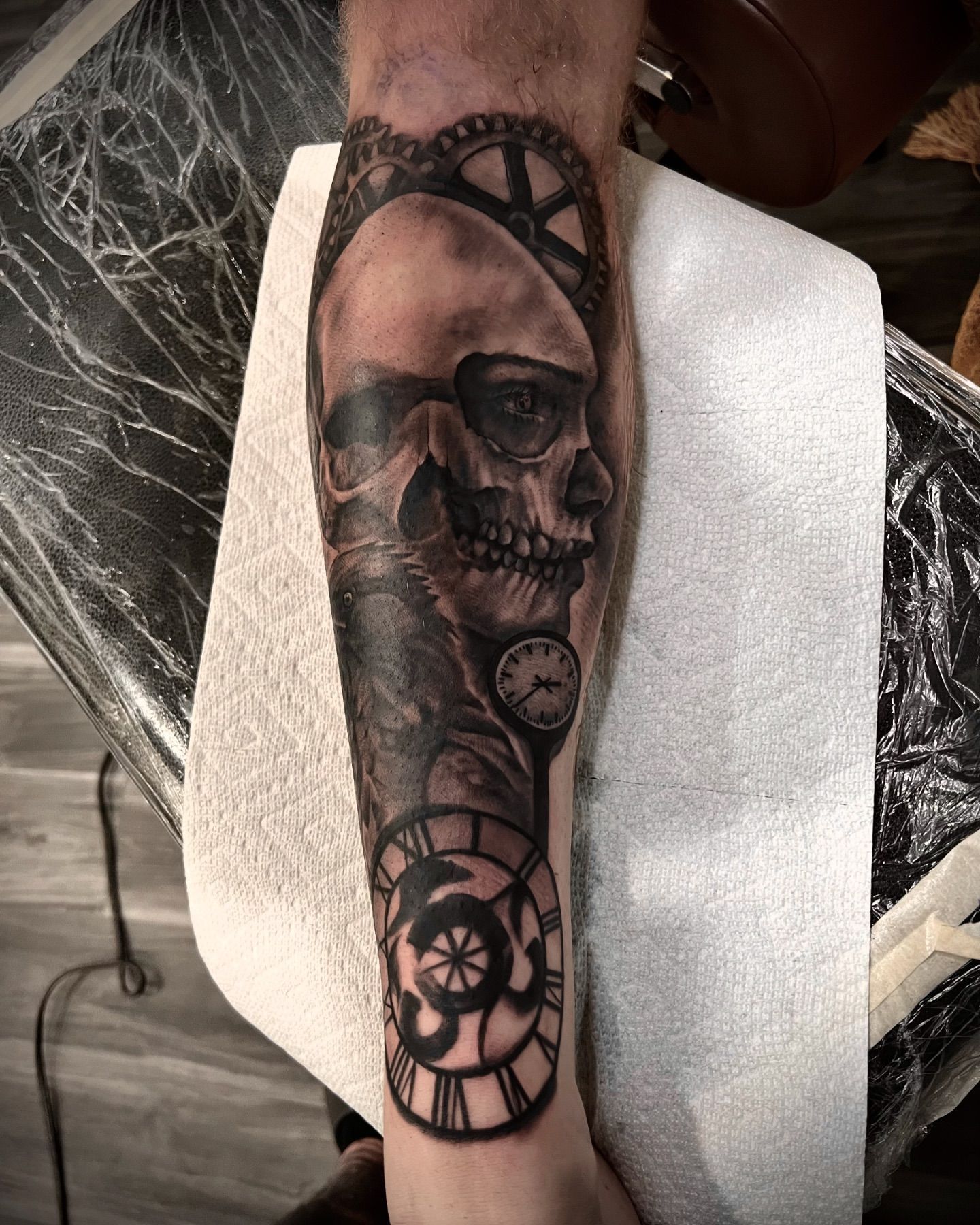 A man has a tattoo of a skull and a clock on his forearm.
